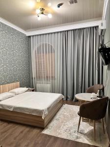 a bedroom with a bed and a desk and a table at STATUS in Shymkent