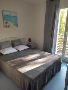 a large bed in a bedroom with a window at Maison 3 chambres avec piscine proche plage in Soulac-sur-Mer +10 photos
