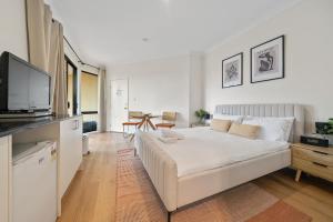 a white bedroom with a large bed and a tv at Newly Renovated Central Private Studio in Pokolbin