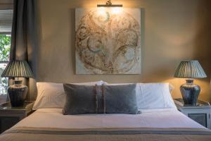a bedroom with a bed with two lamps and a painting at Hotel La Casa del Califa in Vejer de la Frontera