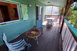 a porch of a house with two chairs and a table at maison en bois in Lacapelle-Viescamp