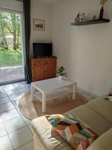 a living room with a white coffee table and a tv at Maison 3 chambres avec piscine proche plage in Soulac-sur-Mer