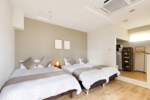 2 camas en un dormitorio con paredes blancas y suelo de madera en Family Inn Nara en Nara