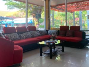 uma sala de estar com um sofá vermelho e uma mesa em กิจตรงวิลล์ รีสอร์ท Kittrongvill em Ubon Ratchathani