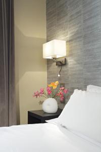 a bedroom with a bed and a vase with flowers on a table at Hôtel Londres et New York - Teritoria in Paris