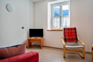 uma sala de estar com uma cadeira e uma televisão em Casa Batistei Ribes em Molveno