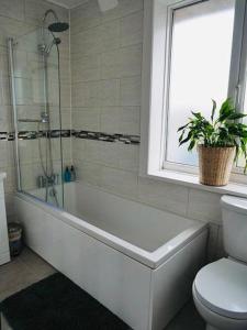 a bathroom with a tub and a toilet and a plant at Elsham Gardens Rooms - Shared Facilities in Manchester