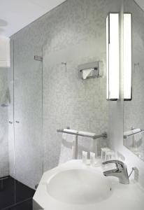 a white bathroom with a sink and a shower at Hôtel Londres et New York - Teritoria in Paris