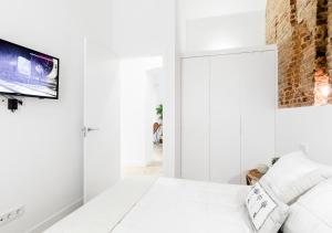 Habitación blanca con cama y TV en la pared en Conde de Peñalver Loft, en Madrid