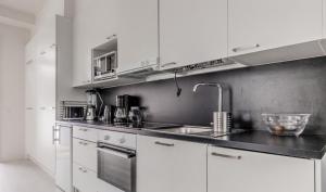 una cocina con armarios blancos y fregadero en Cozy apartment en Espoo