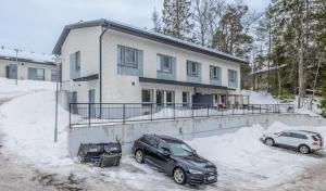 twee auto's geparkeerd voor een huis in de sneeuw bij Cozy apartment in Espoo