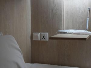 a corner of a room with a bed and a light switch at The Room @ Bugis in Singapore