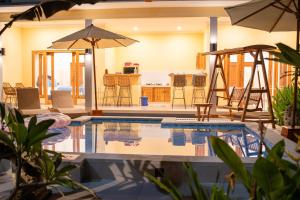 a swimming pool with chairs and an umbrella at Villa Aura in Lovina