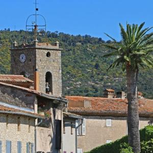 a building with a clock tower and a palm tree at L'Aloe Vera in Plan-de-la-Tour