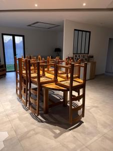 - une rangée de tables et de chaises en bois dans une chambre dans l'établissement Maison à proximité du circuit 24h, à Saint-Gervais en-Belin