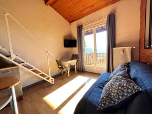 ein Wohnzimmer mit einem blauen Sofa und einem Fenster in der Unterkunft Studette et studio en montagne proche stations de ski et lac in Prunières