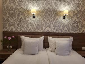 a bedroom with a bed with white pillows and wallpaper at Hotel Maximum in Krakow