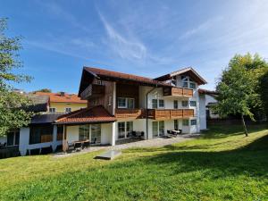 uma casa grande com um jardim relvado à frente em HoFer am Zeitberg Ferienwohnung Wildeck em Bad Kohlgrub