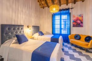 una habitación de hotel con 2 camas y una silla en AL-QUIVIR Suites, en Córdoba