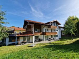 ein großes Haus mit einem Rasenplatz davor in der Unterkunft HoFer am Zeitberg Ferienwohnung Echelsbach in Bad Kohlgrub