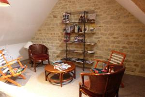 a living room with chairs and a table and a book shelf at Le Clos Hortense in Nonant
