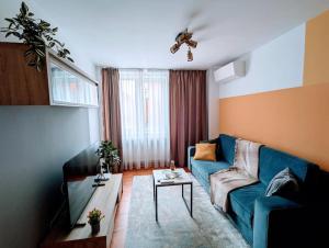 a living room with a blue couch and a tv at Peaceful Victory Square Home in Timişoara