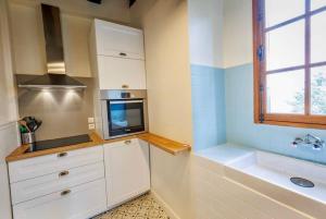 eine Küche mit weißen Schränken, einem TV und einer Badewanne in der Unterkunft Maison du Chapitre in Prudhomat