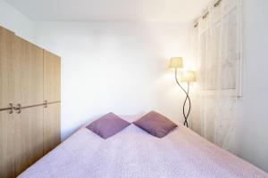 een slaapkamer met een bed met paarse lakens en een lamp bij Le Cap 27 in Cap d'Agde