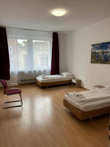 1 dormitorio con 2 camas, ventana y silla en Othman Appartements Falkenstraße 26 en Hannover