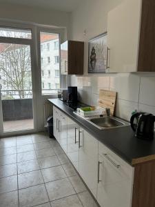 cocina con armarios blancos, fregadero y ventana en Othman Appartements Falkenstraße 26 en Hannover