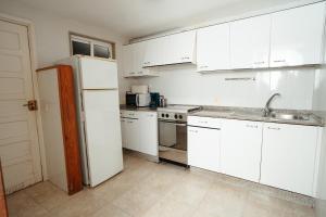 cocina con armarios blancos y nevera blanca en Apartamentos Ancoradoiro en Lariño