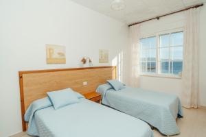 2 camas en una habitación con ventana en Apartamentos Ancoradoiro, en Lariño