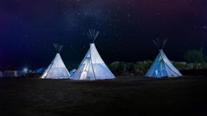 three blue and white tents in a field at night at Alpaka-Tipi-Park in Bad Salzungen