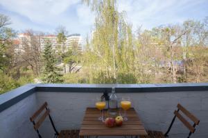 una mesa con 2 vasos de zumo de naranja y fruta en el balcón en Bright apartment by the park & the river, en Wroclaw