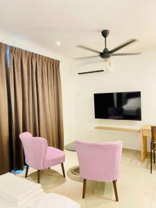 a living room with two pink chairs and a tv at BIG TREE HOTEL in Temerloh