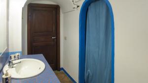 a bathroom with a sink and a blue shower curtain at Lighted Pool, Barbecue & Sea View - Authentic "Dammusi" in Pantelleria