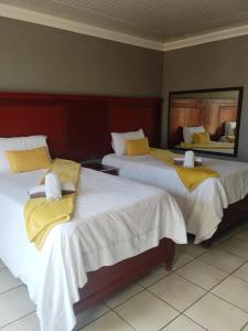 two beds with yellow pillows in a hotel room at Kgakgamela road lodge in Driekop
