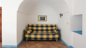 a plaid chair in a corner of a room at Lighted Pool, Barbecue & Sea View - Authentic "Dammusi" in Pantelleria