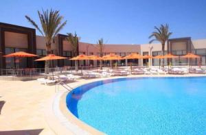 a large swimming pool with orange umbrellas and chairs at App S1 à l'hôtel Andalucia Beach in Bizerte