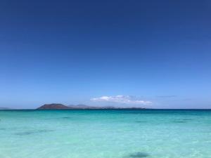 a view of the ocean with mountains in the distance at Dunas Club - Hotel & Apartamentos in Corralejo