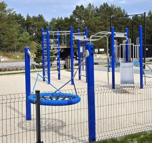 un parco giochi vuoto con telaio blu in un parco di Apartament na wydmie - Porto Łeba a Łeba