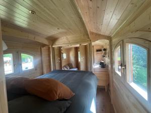 een slaapkamer in een tiny house met 2 ramen bij La Roulotte deluxe de Malpas in Quingey