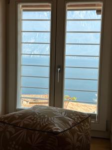 um quarto com duas grandes janelas com vista para o oceano em Studios Al Castello dei Limoni em Limone sul Garda