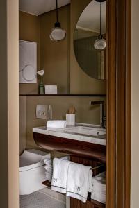 ein Badezimmer mit einem Waschbecken, einem WC und einem Spiegel in der Unterkunft Hotel Norman Paris in Paris