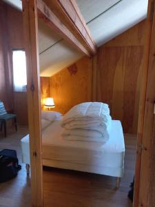 un letto con lenzuola e cuscini bianchi in una stanza di Chalet le Brespail a Boutx