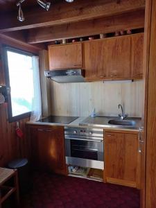 eine Küche mit einem Herd, einer Spüle und Holzschränken in der Unterkunft Chalet le Brespail in Boutx