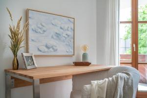 einen Schreibtisch in einem Zimmer mit einem Stuhl und einem Gemälde in der Unterkunft Stilvolle Seewohnung in Utting in Utting am Ammersee