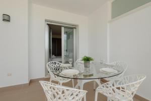 a white dining room with a glass table and chairs at Holiday Apartment La Floresta Elviria in Ojén