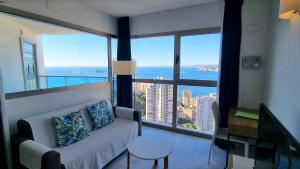 een woonkamer met een bank en een groot raam bij Highrise apartment with private terrace & sea views - 34th floor in Benidorm