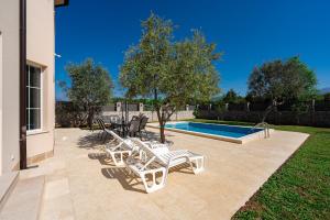 a patio with white chairs and a swimming pool at Villa Stemi in Tivat